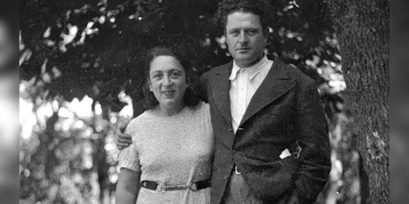 Ağaçların önünde birlikte duran Nazım Hikmet ve Piraye. Fotoğraf siyah beyaz ve eski görünümlü. Piraye solda, açık tenli, omuz hizasında koyu saçlı ve ortadan ayrık; kısa kollu, açık tonlu, diz altına kadar uzanan bir elbise giymiş, belinde tokalı bir kemer, hafif gülümsüyor ve bedenini Nazım’a dönük tutuyor. Nazım sağda, açık tenli, dalgalı ve kabarık koyu saçlı; açık renk yakalı bir gömlek ve üzerine koyu renk, geniş yakalı bir ceket giymiş, elleri ceketinin ceplerinde. İkisi birbirine yakın d