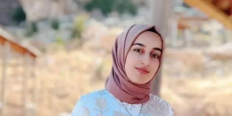 Rojin açık kahverengi tonlarında başörtüsü takmış. Ten rengi buğday, yüz hatları ince, koyu renk kaşları ve kahverengi gözleri var. Dudaklarında hafif bir gülümseme. Üzerinde açık mavi ağırlıklı, pastel tonlarda çiçek desenli bir üst; boynunda ince bir zincir kolye.