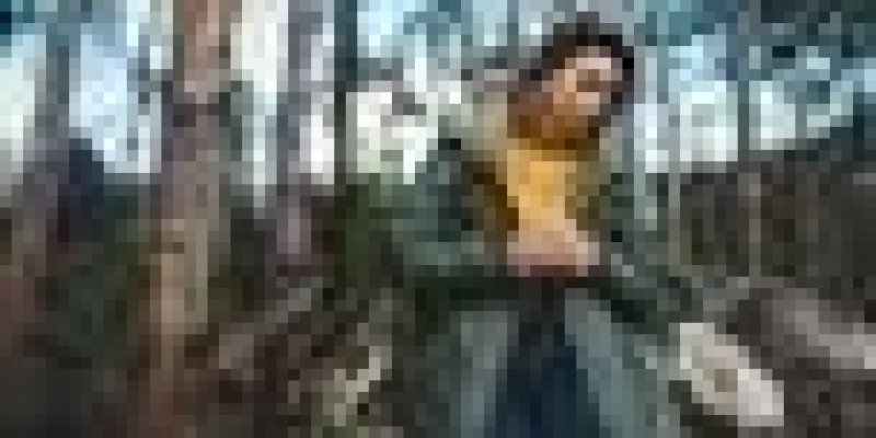 Sonbaharda ormanın içinde yeşil bir kaban giyinmiş orta yaşlı ve açık uzun saçlı bir kadın ayakta, başı önde, ellerini birbirine kavuşturmuş ve düşüncelere dalmış.