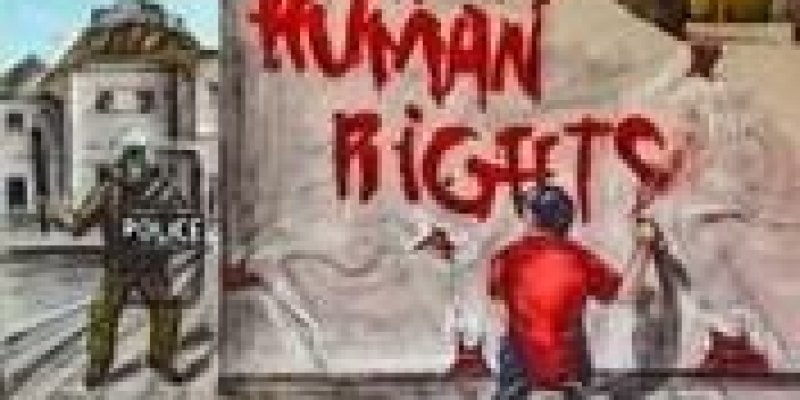 Beyaz bir duvarın önünde arkası dönük dizlerinin üzerine çömelmiş bir erkek, elinde kırmızı sprey boya var. Duvara “İngilizce “İnsan Hakları”, “Human Rights” yazıyor. Duvarın yanında, boya ile yazı yazan adama yönelmiş bir polis resmi kıyafeti ve kalkanıyla görünüyor.