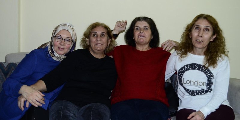Kanepede bir arada olmaktan çok mutlu görünen dört neşeli kadın. Sol başta mavi kazağı ile baş örtülü, gözlüklü orta yaşlarının başındaki kadının eli yanında bulunduğu, yaslandığı siyah kazaklı kadının elinin üstünde. Onun yanındaki siyah kazaklı kadın saçlarını sarıya boyatmış, çizgili fitilli kadife pantolonu var ve sol koluyla da yanındaki kadına sarılmış. Kadın kırmızı kazağıyla iki kadının ortasında olmaktan mutlu görünüyor, kolları havada, kanepenin sırtına yaslanmış şekilde, keyifli. En s