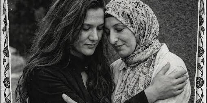 Siyah-beyaz bir afiş/ilan görseli. Üstte büyük puntolu başlık ve altında iki Fatmanur Çelik’in sarıldığı bir fotoğraf; en altta da isimlerin yazdığı bir şerit. Kenarlarda yaprak desenli bir çerçeve. Üst başlık metni: “İKİ FATMA NUR’U DA KORUYAMADIK” Başlığın altındaki metin: “Birliğimiz, yasımız ve umudumuzla... Kalbimizdeler.” Soldaki Çelik uzun, dalgalı koyu renk saçları açık; koyu renk bir üst giyiyor. Sağdaki Çelik desenli bir başörtüsü takıyor ve açık renk bir kıyafet giyiyor. İkisinin de g