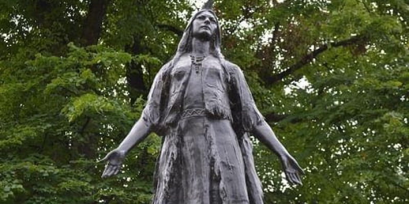 Ormanda bir kadın heykeli var. Kadın iki ellerini iki yana açmış ve karşıya bakıyor.