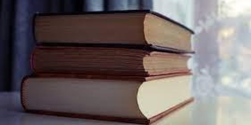 Pencereden günışığı sızan bir fonun önünde beyaz bir masa üzerinde üç tane orta kalınlıkta kitap üst üste duruyor.