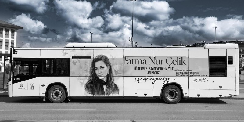 Üzerinde büyük bir anma yazısı ve Fatmanur Çelik’in portresi bulunan beyaz bir şehir otobüsü yandan görüntülenmiş ve gövdesinin orta kısmında siyah-beyaz bir kadın portresi ile etrafa dağılmış kuş silüetleri. Portre yanında büyük puntolarla “Fatma Nur Çelik” yazıyor. Altında “ÖĞRETMENİ SAYGI VE RAHMETLE ANIYORUZ.” ifadesi. Daha aşağıda el yazısı stilinde “Unutmayacağız...” yazıyor. Sağ tarafta küçük yazıyla bir alıntı: “DÜNYANIN HER TARAFINDA ÖĞRETMENLER İNSAN TOPLULUĞUNUN EN FEDAKÂR VE EN SAYGI