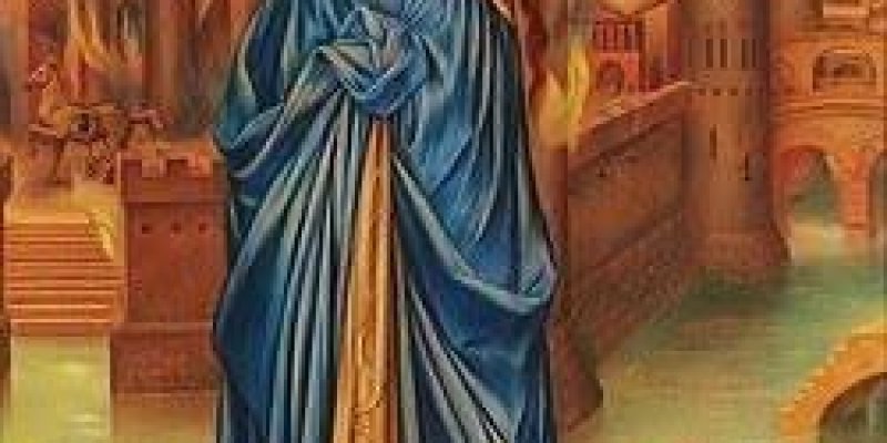 Kassandra’nın uzun kızıl saçlı, mavi elbiseli, figürü, yanan bir şehrin önünde kayalıkların üzerinde ayakta duruyor. Saçları dalgalı ve beline kadar uzanıyor, başında ince altın renkli bir taç ya da bant. Kolları iki yana kalkmış, elleriyle saçlarını kavramış; duruşu hem güçlü hem de dramatik bir ifade taşıyor. Üzerinde belden toplanmış, dökümlü, parlak mavi bir elbise ve önde altın rengi bir kumaş parçası; elbise kat kat ve hafifçe rüzgâr esiyormuş gibi kıvrımlı. Ayaklarında açık, kayışlı sanda