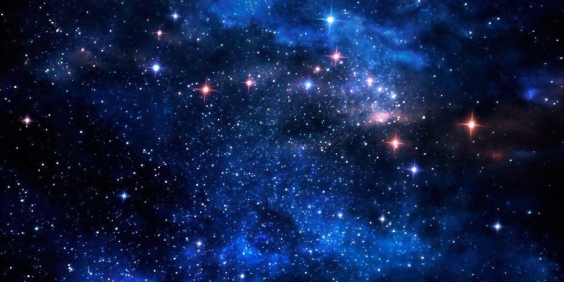 Yıldızlarla dolu, mavi tonların baskın olduğu bir uzay görüntüsü. Koyu siyah arka planın üzerinde çok sayıda küçük beyaz yıldız noktası ve bazıları daha parlak, ışın saçan yıldızlar görülüyor. Görüntünün orta ve üst kısımlarında bulutsu gibi duran, dumanımsı mavi bulutlar yayılıyor; sağ orta bölgede pembe-kızıl tonlu daha parlak bir leke ve çevresinde birkaç parlak yıldız var.