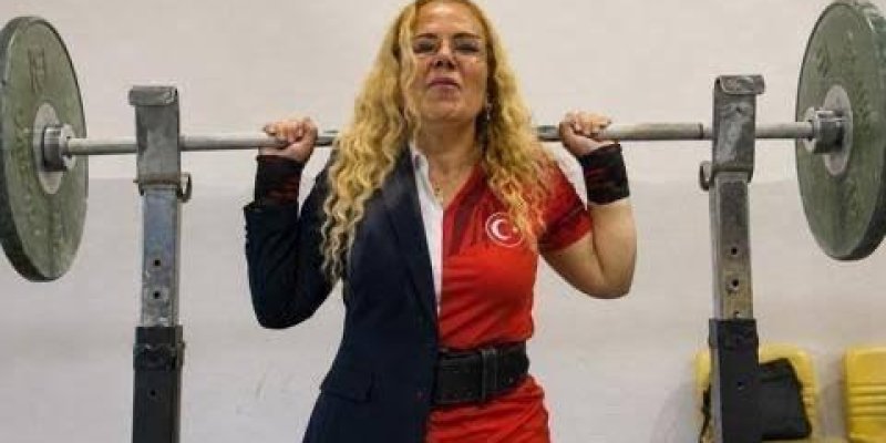 Spor salonunda halter kaldıran Döndü Kanat, omuz hizasında, iki yanında ağırlık plakaları olan bir halter barını kavramış. Orta tenli, bel hizasına inen kıvırcık sarı saçlı ve gözlüklü. Üzerinde ilginç bir kıyafet var: vücudunun sol tarafında lacivert bir takım elbise ceketi, sağ tarafında kırmızı renkte, göğüs kısmında beyaz ay-yıldız bulunan bir tişört ya da forma; iki parça ortadan tam dikey şekilde birleşmiş. Belinde siyah bir ağırlık kemeri takılı. Bileklerinde koyu renk bileklikler veya ba