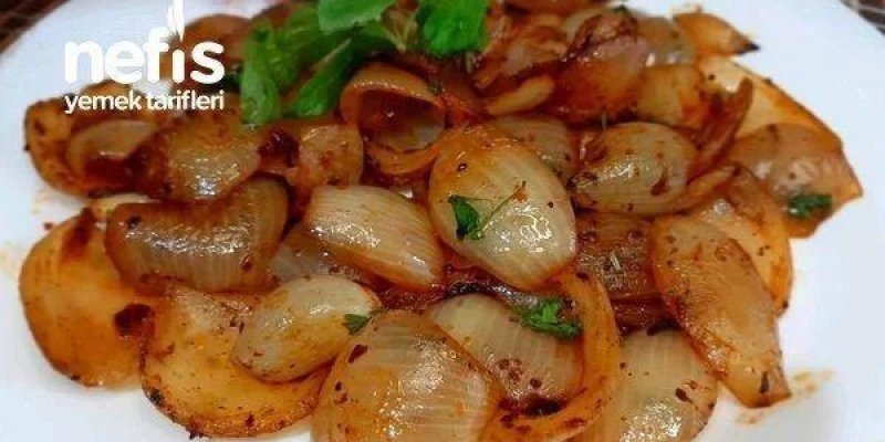 Beyaz bir tabakta pişmiş arpacık soğan ve patates dilimlerinden oluşan bir yemek. Soğanlar parlak ve hafif karamelize; patatesler yuvarlak dilimler halinde. Üzerinde ince doğranmış yeşillik parçaları ve ortada birkaç dal taze yeşil ot. Sol tarafta “nefis yemek tarifleri” yazısı.