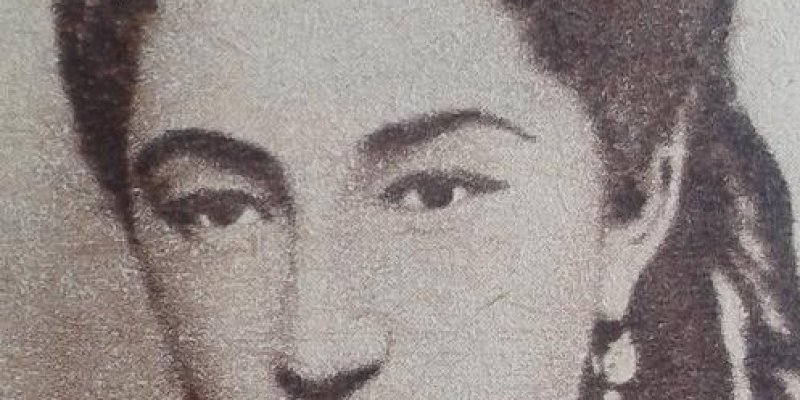 Siyah beyaz fotoğraf. Seniha Sultan’ın portresi. Saçları tepeden kabarık ve arkaya doğru taranmış. Saçlarının arasında ince bir örgü görünüyor. Uzun küpeler takmış ve geleneksel bir kıyafet giymiş gibi görünüyor. Yüz ifadesi ciddi ve bakışları doğrudan kameraya yönelik.