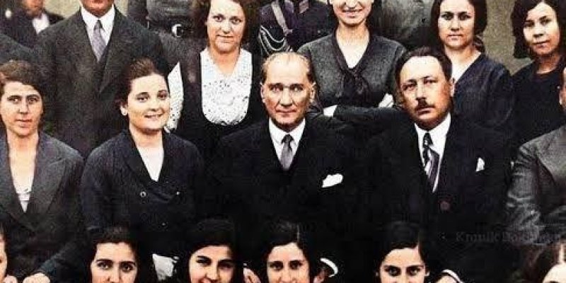 Çoğu kadın olan yaklaşık yirmi kadar kişi üç sıra halinde duruyor ve oturuyor. Ortadaki sıranın tam ortasında, koyu renk takım elbiseli, kravatlı, kısa saçlı, açık tenli Atatürk öne doğru belirgin şekilde konumlanmış. Sağında ve solunda koyu renk takım elbiseler giymiş iki erkek oturuyor; biri bıyıklı, diğeri daha ince yüz hatlarına sahip. Ön sırada oturan kadınlar açık renk, çoğunlukla gri tonlarında elbiseler giymiş; yakalarında fular veya süs detayları. Orta ve arka sıradaki kadınların çoğu k