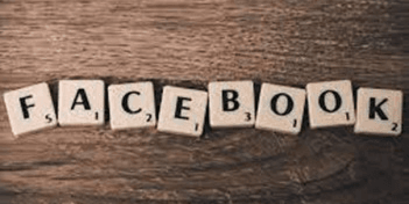 Ahşap bir zemin üzerinde kemik renginde facebook yazılmış okey taşları var.
