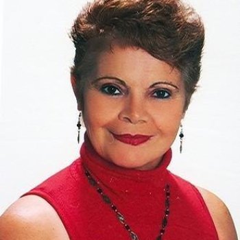 Kırmızı balıkçı yaka kolsuz üst giymiş, kısa kahverengi saçlı. Arka plan beyaz. Kameraya dönük ve hafif gülümsüyor. Dudaklarında kırmızı ruj var. Göz makyajı belirgin, kaşları şekilli. Ten rengi açık. Kulaklarında sarkık küpeler. Boynunda siyah boncuklu bir kolye.