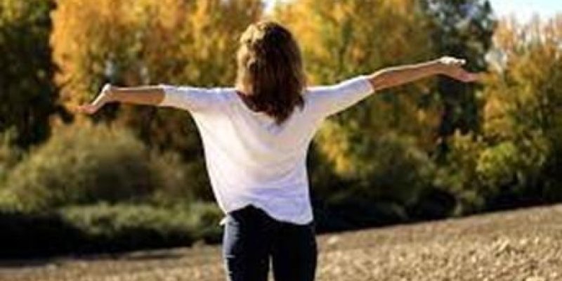 Sararmış yaprakları olan ağaçların olduğu doğal güneşli bir ortamda arkası dönük genç bir kadın sırtı dönük şekilde kollarını yanlara açmış ayakta duruyor. Kadın dalgalı uzun saçlı, beyaz uzun kollu bir bluz, siyah kot pantolon giyinmiş.