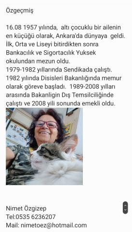 Kısa dalgalı saçlı ve gözlüklü, gülümseyerek bir kediyle birlikte selfie çekmiş. Üzerinde kamuflaj desenli bir tişört var. Kedi beyaz ve gri renkli, uzun tüylü.