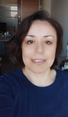 Yazarın güler yüzlü objektife gülümseyen fotoğrafı. Kısa, koyu kahve saçları, hafif ve zarif makyajıyla orta yaşlı görünüyor.