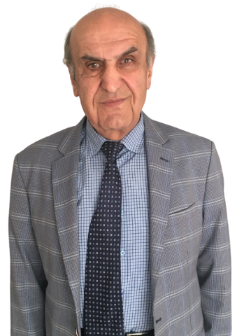 Gri ceketi, içinde mavi kareli gömleği ve lacivert üzerine açık renk kutucuk desenli kravatıyla. Gri, biraz dökülmüş saçlarıyla gülümsüyor.