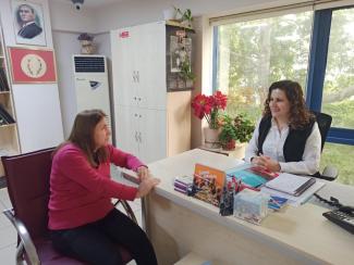 Kütüphanede masanın çevresinde 2 kadın karşılıklı konuşuyor.