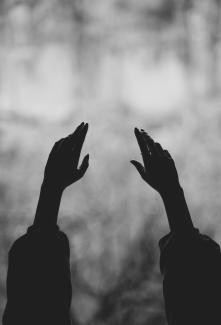 Bir kadının açık havaya doğru uzanmış elleri. Siyah beyaz bir resim.