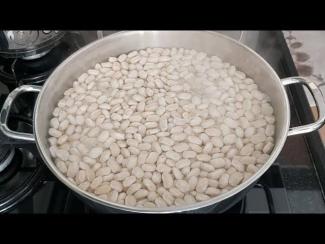 Turuncu sandalyelerin ve beyaz dolapların olduğu mutfakta mavi kazaklı genç bir kadın ocağın başında tencerede keyifle yemek pişiriyor.