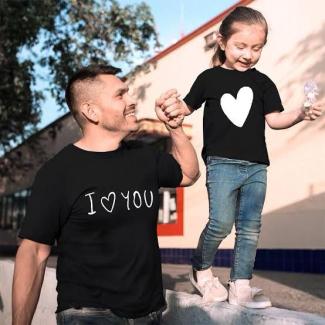 Bir adam ve küçük bir kız çocuğu el ele tutuşmuşlar. Adamın üzerinde "I ♥ YOU" yazılı siyah bir tişört, küçük kızın üzerinde büyük beyaz bir kalp bulunan siyah bir tişört var. Kız çocuğu kot pantolon ve beyaz spor ayakkabı giymiş. İkisi de mutlu görünüyor ve adam kıza sevgi dolu bir şekilde bakıyor. Arka planda ağaçlar ve bir bina var. Kız çocuğu elinde bir dondurma tutuyor.