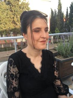 Siyah dantel detaylı elbise giymiş Hasibe Boztepe’nin saçları yukarıdan toplanmış ve önde birkaç tutam saç yüzüne düşüyor. Gözleri kapalı ve hafifçe gülümsüyor. Arka planda açık havada, çiçeklerin ve ağaçların olduğu bir ortamda oturuyor. Yanında beyaz plastik bir sandalye ve büyük bir saksıda lavanta benzeri mor çiçekler var. Gün ışığı ortamı aydınlatıyor.