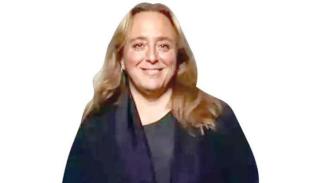 Açık renk uzun saçlı, orta yaşlarda Ayşe Barım. Üzerinde koyu renk bir kıyafet var. Arka plan tamamen beyaz ve sade. Gülümsüyor ve doğrudan kameraya bakıyor.