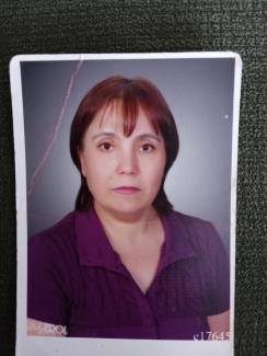 Kısa, kızıl, düz saçları ve kâkülleri; kısa kollu, örgülü, mor bluzuyla pembe rujuyla kendinden emin görünüyor.