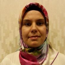 Genç, beyaz kazağı, çiçekli eşarbıyla gülen gözleriyle görülüyor.