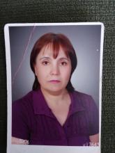 Kısa, kızıl, düz saçları ve kâkülleri; kısa kollu, örgülü, mor bluzuyla pembe rujuyla kendinden emin görünüyor.