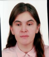 Uzun, kahverengi saçları, açık pembe bluzu, top küpeleri var.