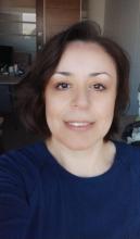 Yazarın güler yüzlü objektife gülümseyen fotoğrafı. Kısa, koyu kahve saçları, hafif ve zarif makyajıyla orta yaşlı görünüyor.